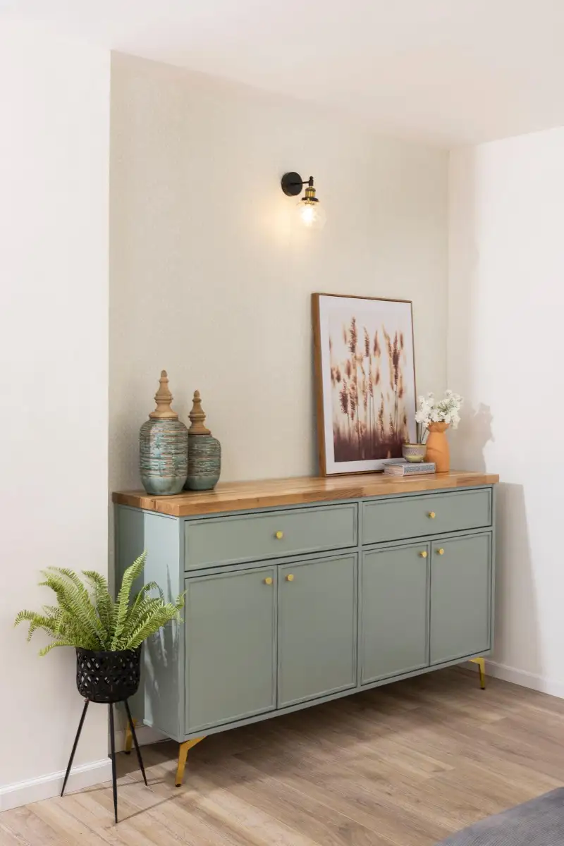 Sage green console styled with ceramics and a framed print