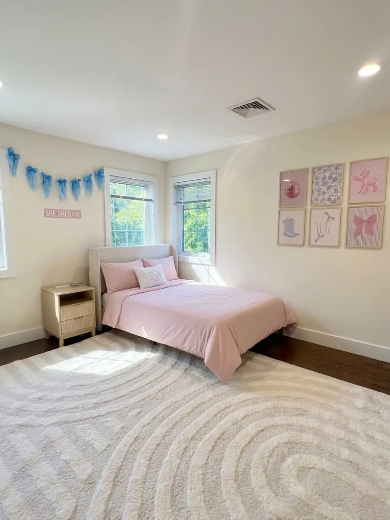 Girl’s bedroom with a pink bed and framed drawings