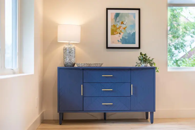 Navy dresser styled with a lamp, plant and framed print