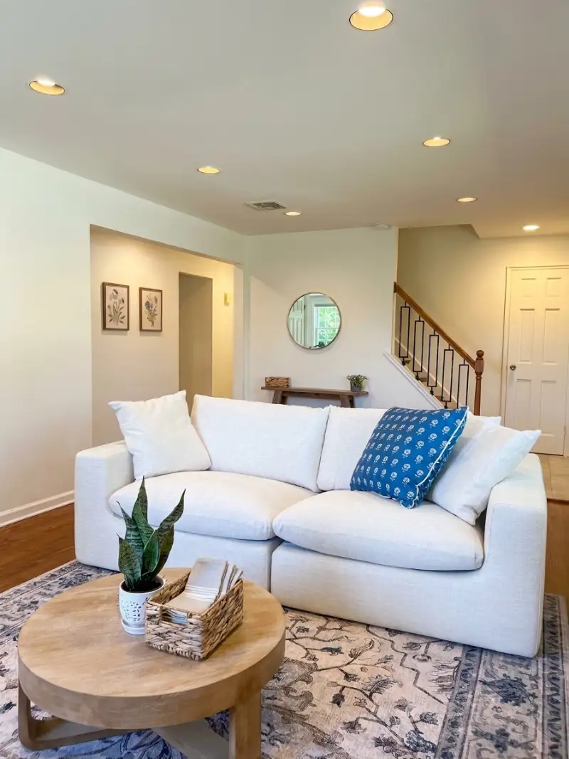 Living room with a white sectional and a round wood coffee table